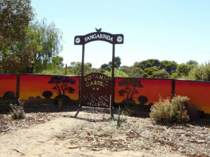 Entrance sign to Pangarinda Botanic Garden with painted sunset mural in the background.