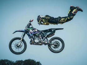 Motocross rider performing a mid-air stunt while fully extended behind the bike.