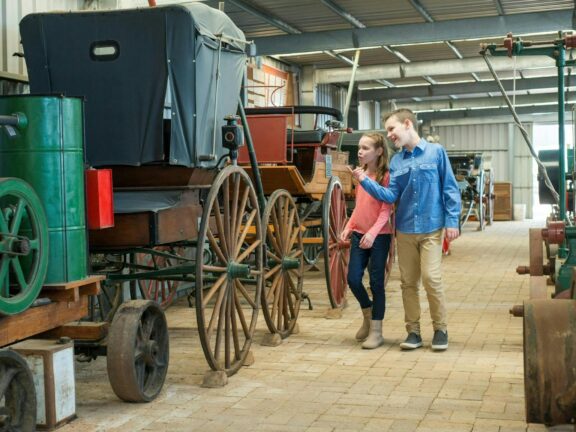 Couple of kids looking at old carriages in a museum