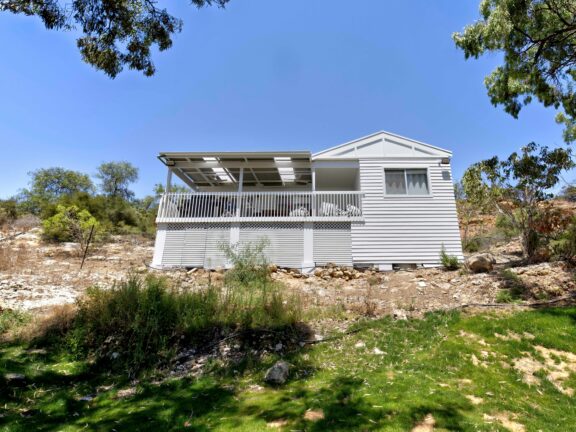 White house with a deck on slope