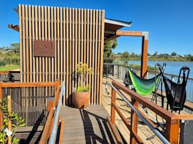 ramp to a balcony with two hammocks overlooking a river