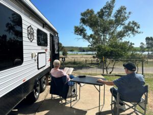 Elderly couple relaxing under the sun outside their caravan
