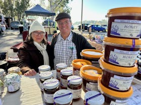 Elderly couple posing with table full of Mallee honey jars