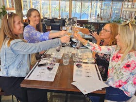 four women at a wine tasting raising their glasses