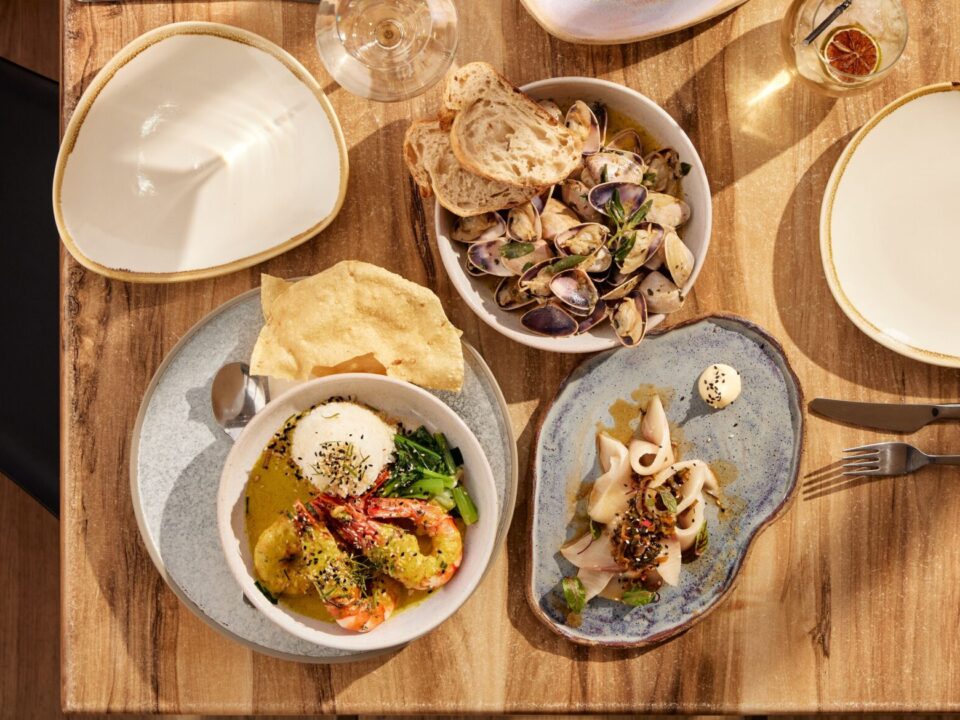 Various plates with different seafood on a table alongwith a couple of empty plates